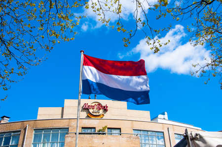 AMSTERDAM-APRIL 30: Holland flag and Hard Rock Cafe signage on the backgroud on April 30,2015. Hard Rock Cafe Amsterdam offers an immersive experience in the waterside restaurant and cocktail bar.のeditorial素材