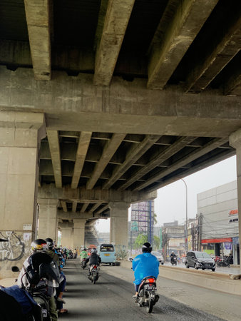 Unidentified people riding a motorbike under the bridge in Jakarta, Indonesia.の写真素材
