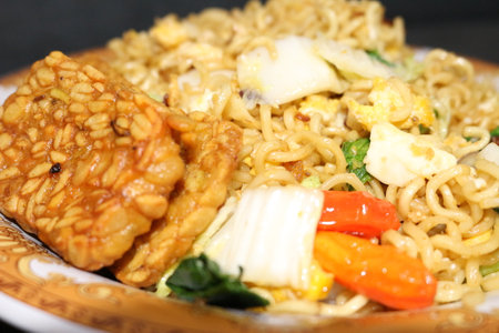 Fried noodle (mie goreng) with vegetables and spices on a black background. top view. Delicious Indonesian Food.の写真素材