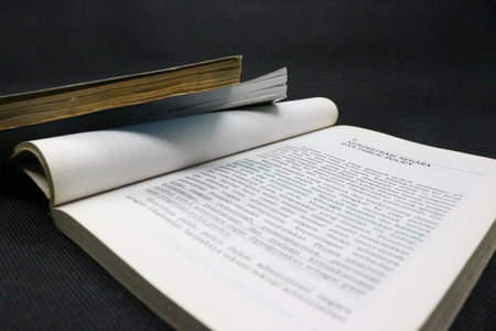 Old book with a bookmark on a black background. 
Open book with a bookmark on a black background, close-up. Copy space. Selective focus.の写真素材