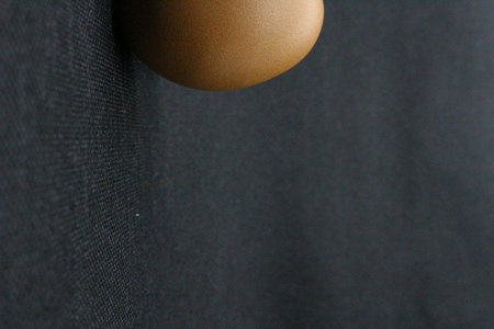 Close-up of a brown lamp hanging on a black wall.の写真素材