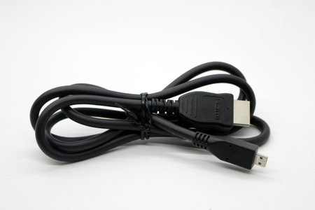 Black monitor cable that is neatly rolled up on a white background