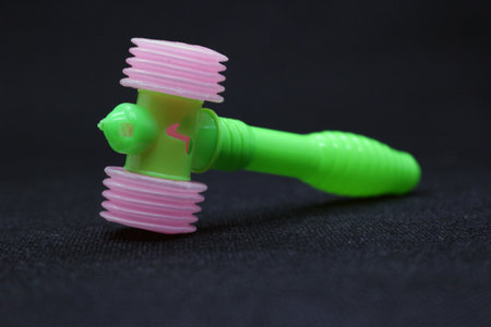 Green little hammer toy for kids on black background