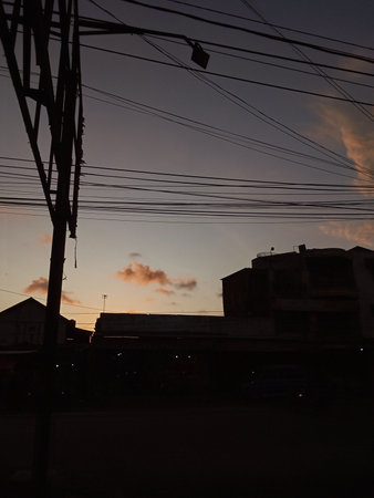 Silhouettes of houses and power lines in the eveningの写真素材