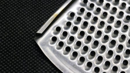 Small metal cheese grater isolated on black background