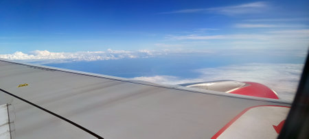 The view outside the plane from the window shows beautiful clouds and green land.