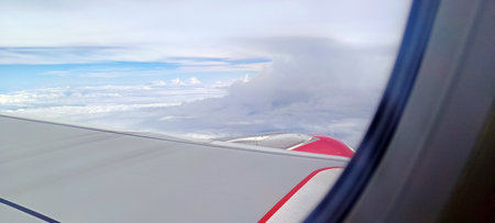 The view outside the plane from the window shows beautiful clouds and green land.