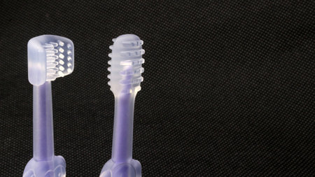 Baby toothbrush with various types of brush heads, black background.