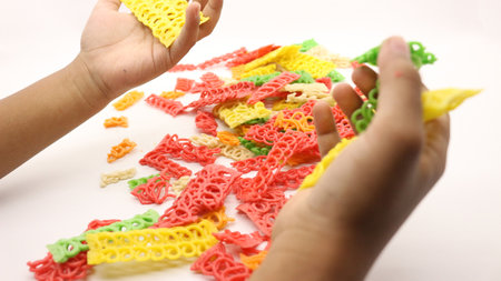 Hand holding colorful crackers or krupuk unfired isolated on white backgroundの写真素材