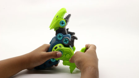 Child's hand playing with dinosaur toy on white backgroundの写真素材