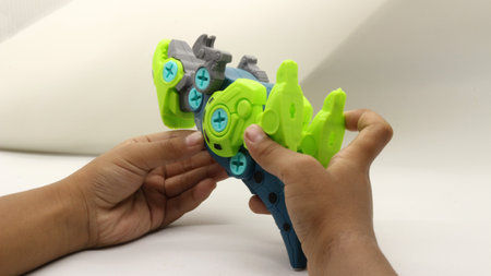 Child's hand playing with dinosaur toy on white backgroundの写真素材