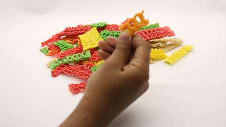 Hand holding colorful crackers or krupuk unfired on white backgroundの写真素材