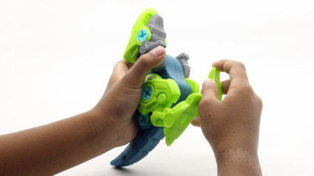 Child's hand playing with dinosaur toy on white backgroundの写真素材