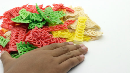 Hand holding colorful crackers or krupuk unfired isolated on white backgroundの写真素材