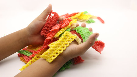 Hand holding colorful crackers or krupuk unfired isolated on white backgroundの写真素材