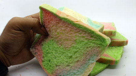 Hand holding sliced rainbow bread isolated on white backgroundの写真素材