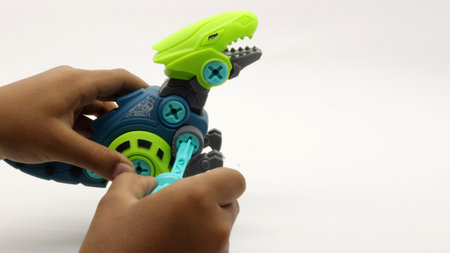 Child's hand playing with dinosaur toy on white backgroundの写真素材