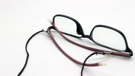 Brown glasses with black eyeglass strap on white background.の写真素材