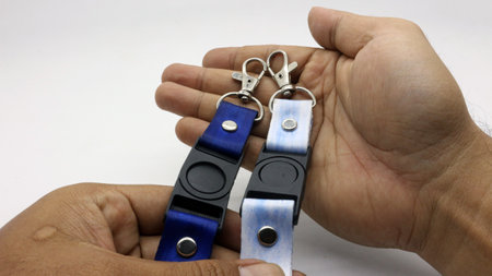 The neck lanyard is held by an adult's hand on a white background