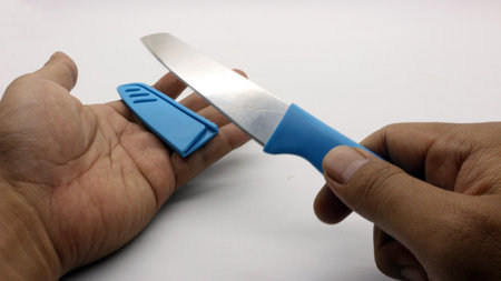 Hand holding blue knife with cover isolated on white background