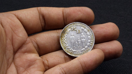 Hand holding an old Indonesian five rupiah coin