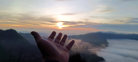Hand pointing to Sunrise mount bromo in East Java, Indonesiaの写真素材
