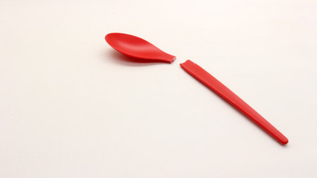 Broken red plastic spoon isolated on white backgroundの写真素材