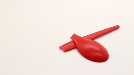 Broken red plastic spoon isolated on white backgroundの写真素材