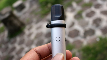 Man's hand holding a small silver vape