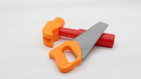 Plastic toy hand saw and hammer isolated on white background
