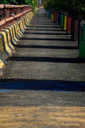 A commuter train moves along a curved railway under overhead electrical lines, surrounded by trees and greenery. The dynamic composition captures motion, transportation, and modern rail infrastructure.の写真素材