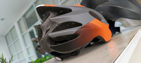 Black and orange bicycle helmet on a white shelfの写真素材