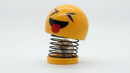 Yellow spring toy with emoji face on white background