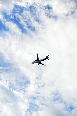 Airplane flying high above with blue sky and white clouds background