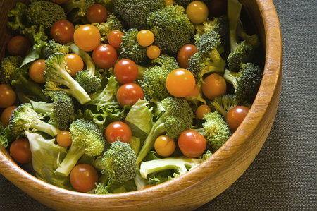 Close up of a fresh salad with ingredients picked directly from an organic garden.  Lettuce, brocolli and cherry tomatoes are displayed in a wooden bowl and will entice a sudden appetite for vegetarians and carnivores alike!の写真素材