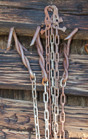 Some old metal chains and traps hang on the exterior wall of a log cabin.の写真素材