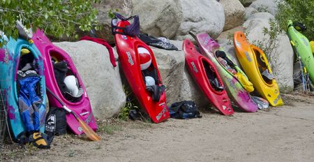 Several competition kayaks with their riders' gear are propped up on the boulders along the Arkansas River, awaiting the next race.のeditorial素材