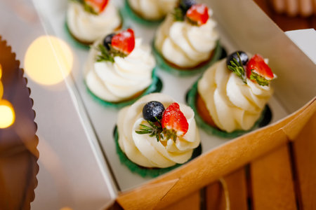 Cupcakes with cream cheese frosting and berries in a boxの写真素材
