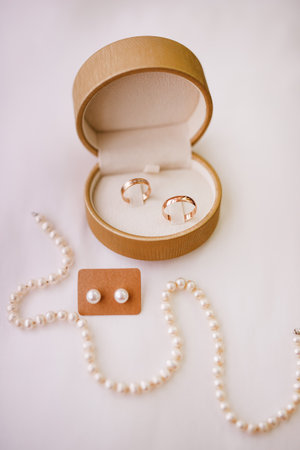 Wedding rings in a box with pearls on a white background