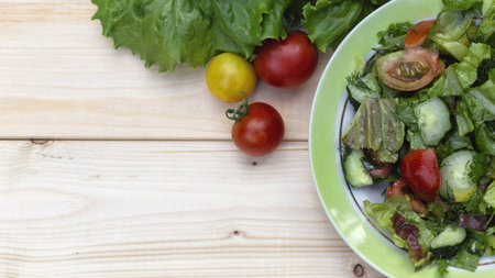 Fresh salad with tomatoes, cucumbers and lettuce on a wooden backgroundの写真素材