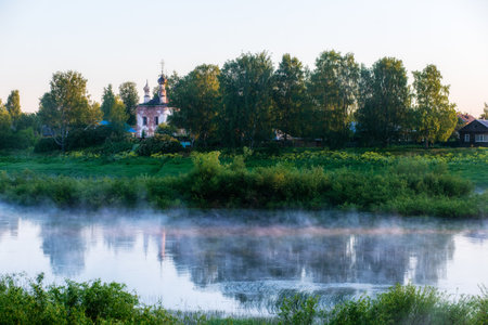 landscape with a church on the bank of the river in the morning mistの写真素材