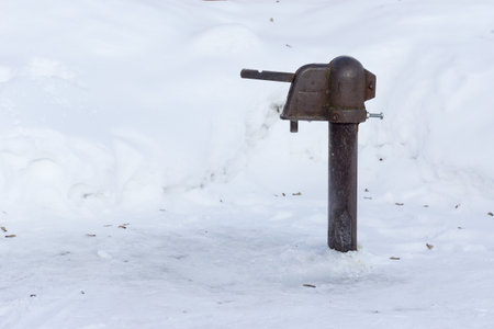 Old rusty water pump in the snow, closeup of photo.の写真素材