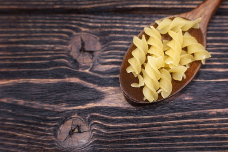 Raw pasta in a wooden spoon on a wooden background. selective focus.の写真素材