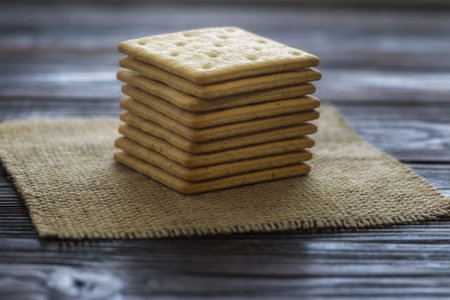 Stack of crackers on burlap cloth on wooden table, selective focusの写真素材