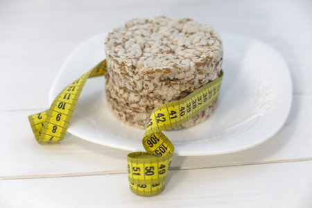 Healthy eating, dieting and weight loss concept - close up of oatmeal and measuring tapeの写真素材