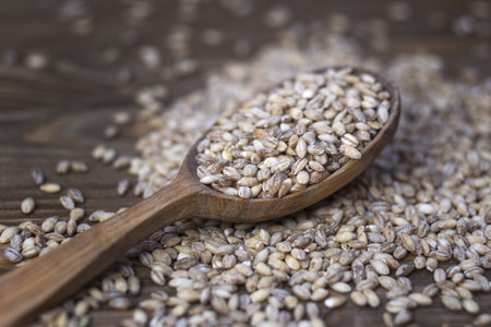 Heap of wheat grains in a wooden spoon on a wooden backgroundの写真素材