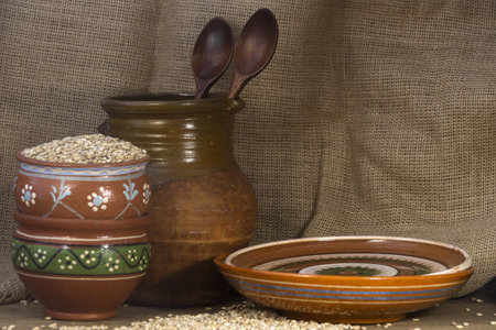 Ceramic bowls with grains and wooden spoons on sackcloth backgroundの写真素材