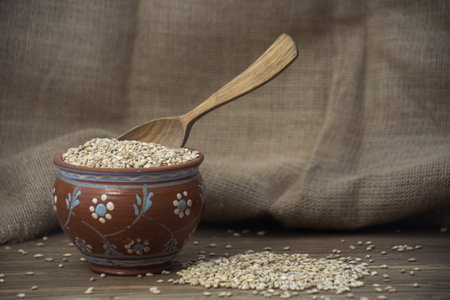 Bowl of quinoa seeds and wooden spoon on sackcloth backgroundの写真素材
