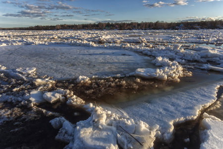 Winter landscape with ice on the river and blue sky at sunset.の写真素材