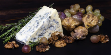 Grape, blue cheese, walnuts and rosemary on a black plateの写真素材